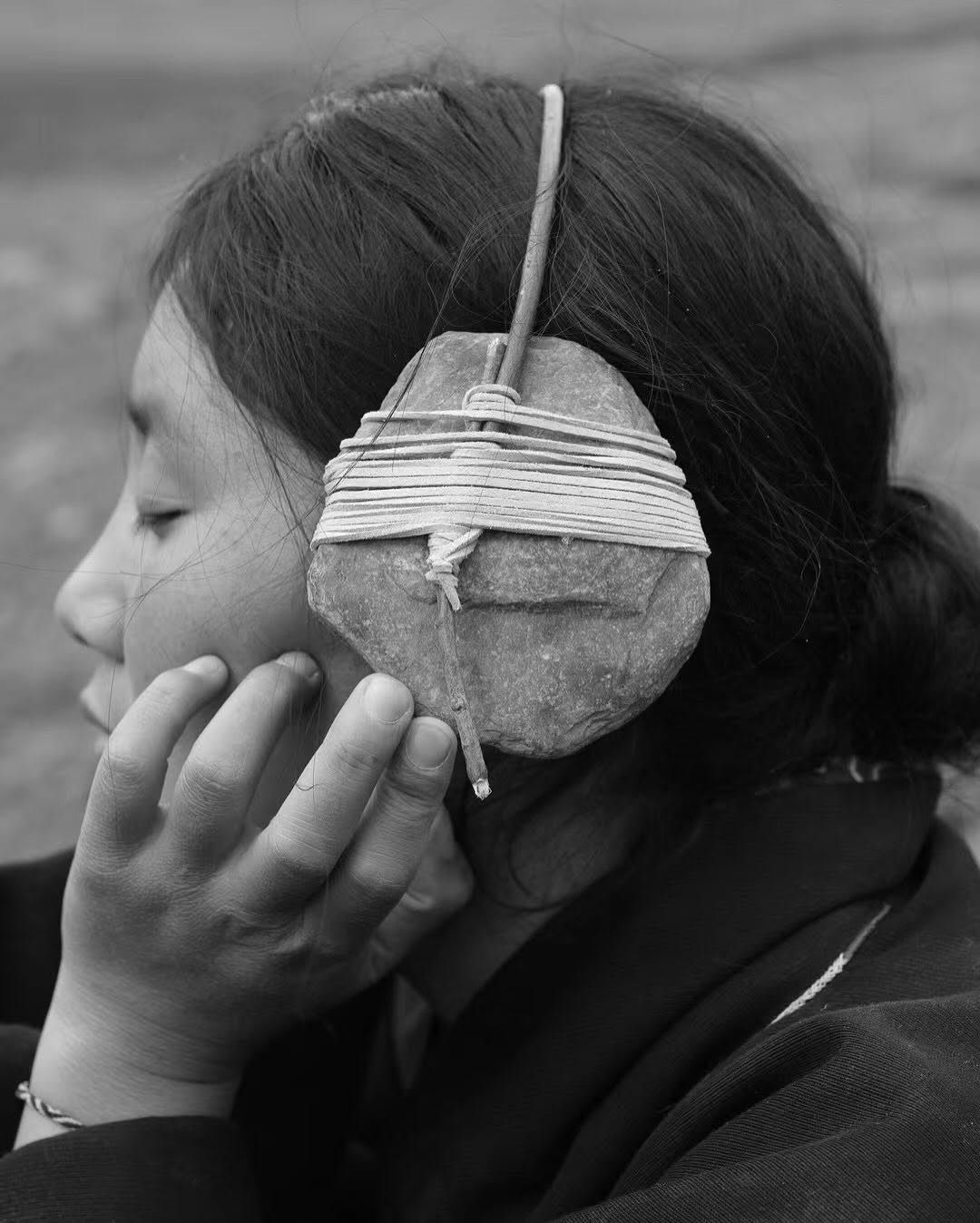 A person listening to a rock held to their ear
